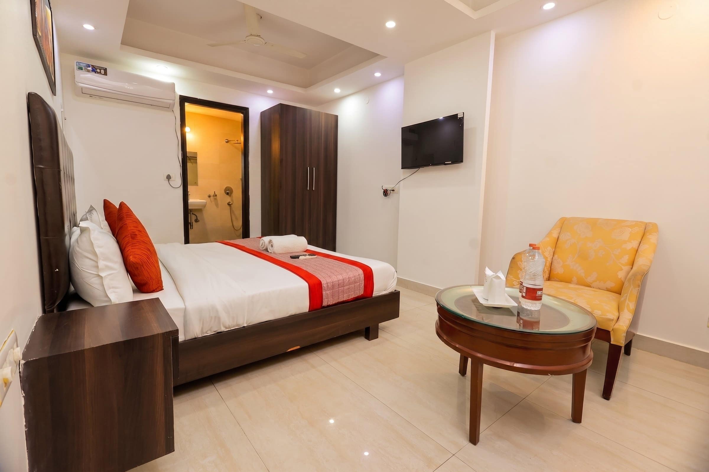 A room with an armchair, mirror and wall-mounted TV