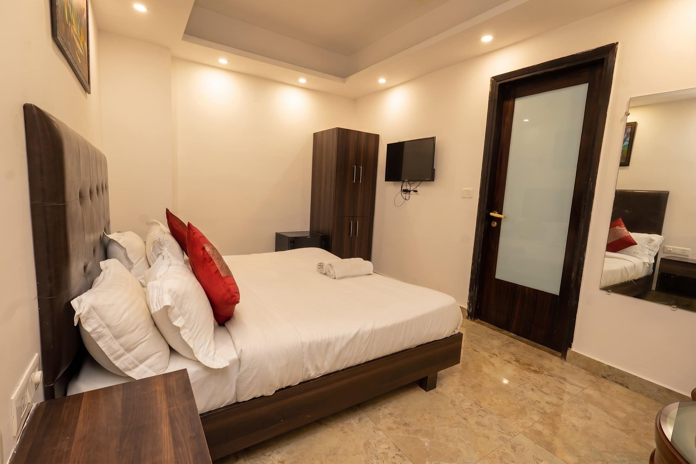 A room with a full-height mirror beside the bed